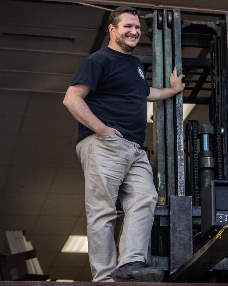 Kyle Rhodes at the KSR shop, standing on a forklift with a KSR Gemini amplifier head